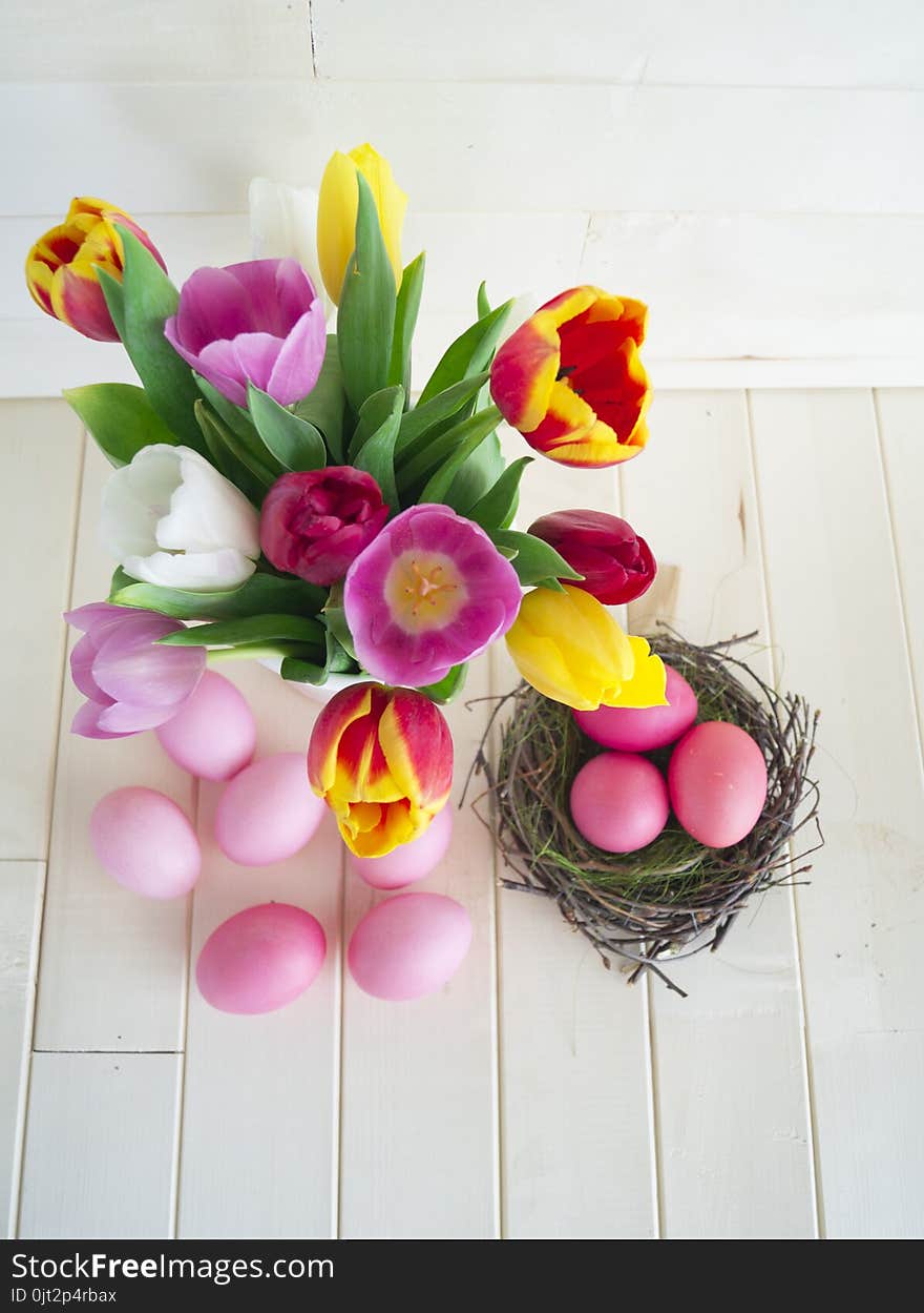 Easter. Pink easter eggs and tulips lie on a wooden background. Flat lay.