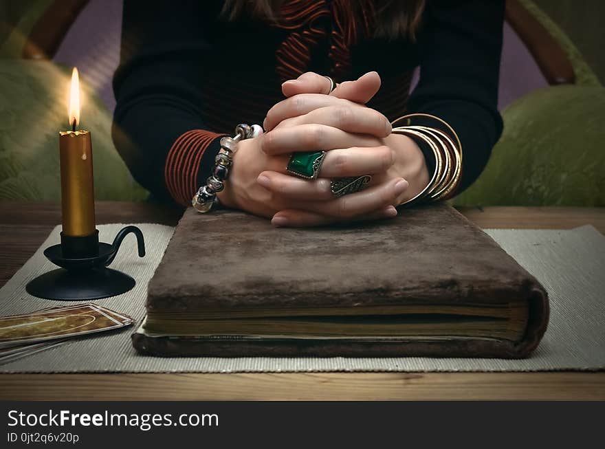 Book of magic. Tarot cards on fortune teller desk table. Future reading. Woman witch reads a ancient magic scroll book and learn art of prediction on wooden table. Book of magic. Tarot cards on fortune teller desk table. Future reading. Woman witch reads a ancient magic scroll book and learn art of prediction on wooden table.