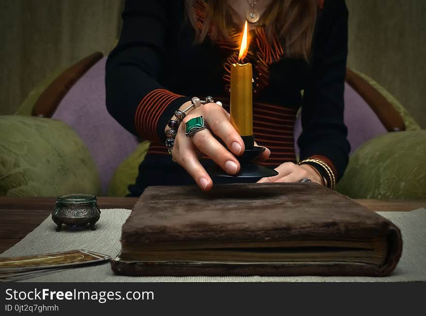 Book of magic. Tarot cards on fortune teller desk table. Future reading. Woman witch reads a ancient magic scroll book and learn art of prediction on wooden table. Book of magic. Tarot cards on fortune teller desk table. Future reading. Woman witch reads a ancient magic scroll book and learn art of prediction on wooden table.