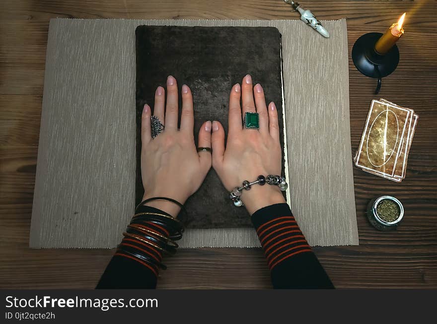 Book of magic. Tarot cards on fortune teller desk table. Future reading. Woman witch reads a ancient magic scroll book with copy space and learn art of prediction on wooden table. Book of magic. Tarot cards on fortune teller desk table. Future reading. Woman witch reads a ancient magic scroll book with copy space and learn art of prediction on wooden table.