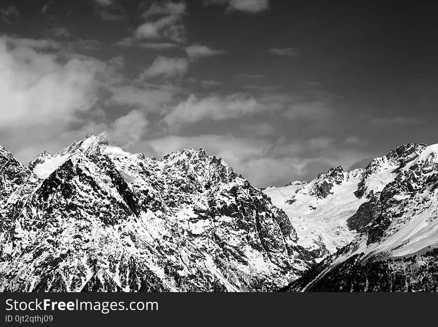 Snowy rocks at sunny day. View from chair lift on Hatsvali, Svaneti region of Georgia. Caucasus Mountains. Black and white toned landscape