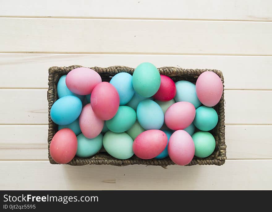 Easter.Pastel colored eggs.Spring composition.Flat ley.Many Easter eggs lie in a container for eggs. Curly eggs.Handmade.Wooden background. Basket woven