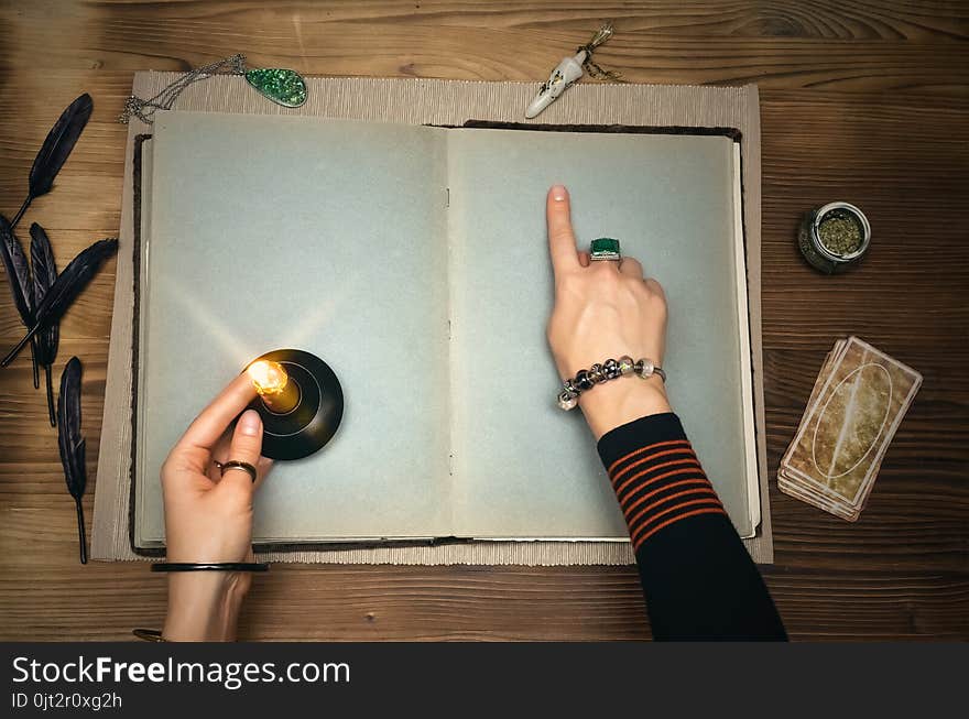 Book of magic. Tarot cards on fortune teller desk table. Future reading. Woman witch reads a ancient magic scroll book with copy space and blank pages and learn art of prediction on wooden table. Book of magic. Tarot cards on fortune teller desk table. Future reading. Woman witch reads a ancient magic scroll book with copy space and blank pages and learn art of prediction on wooden table.