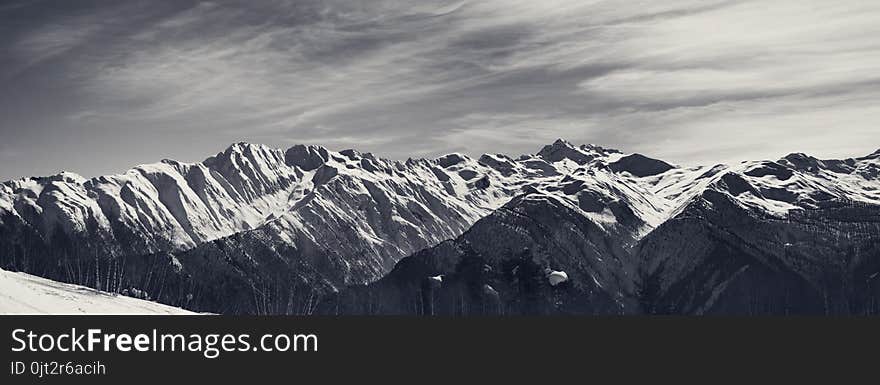 Panoramic view on sunlight snowy mountains in nice morning. Caucasus Mountains. Svaneti region of Georgia. Black and white toned landscape.