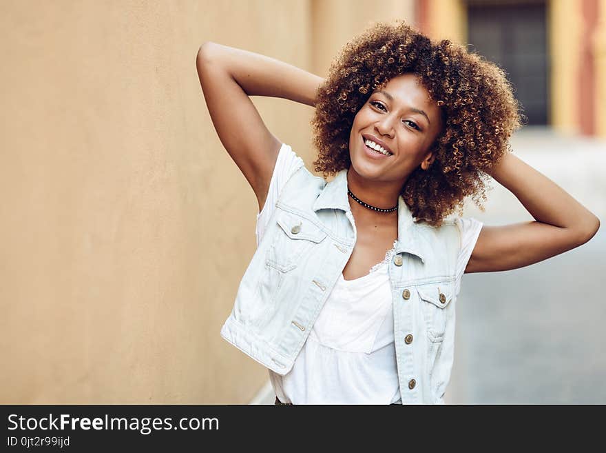 Young black woman, afro hairstyle, smiling in urban background