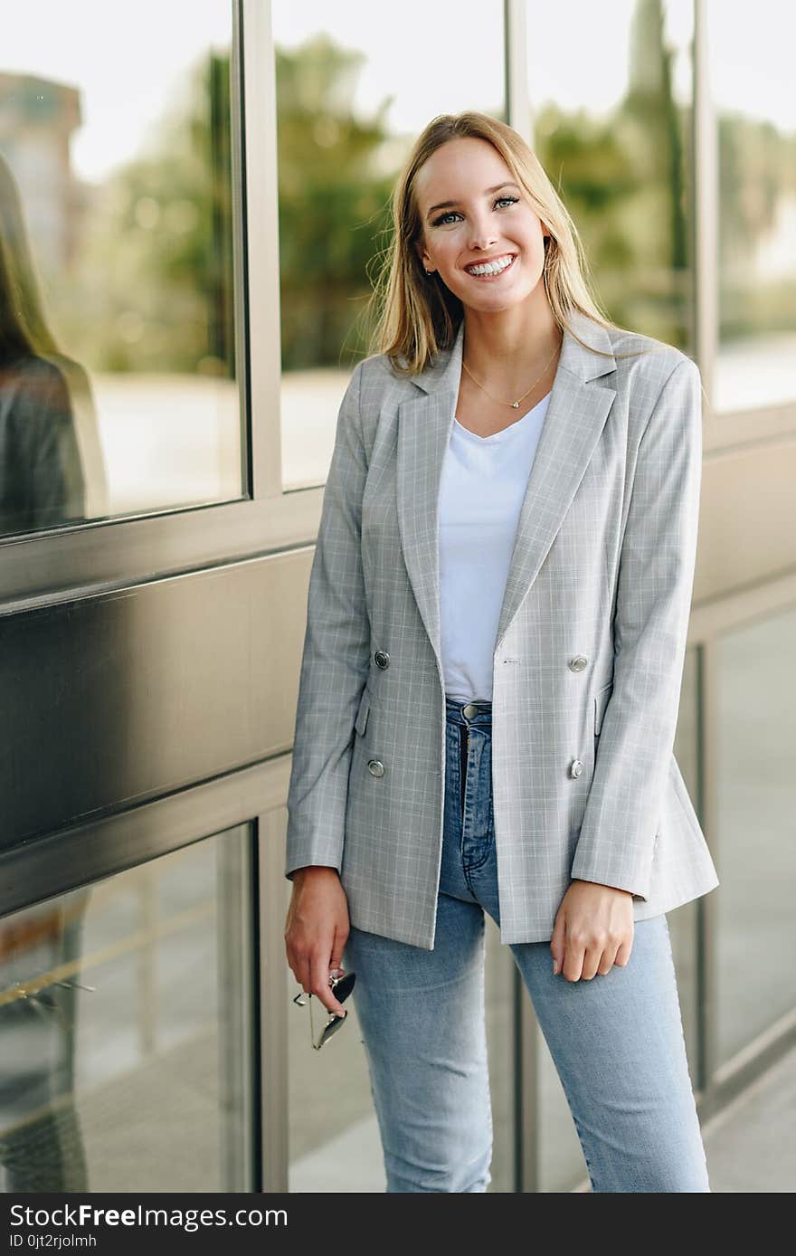 Beautiful young blonde woman smiling in urban background.