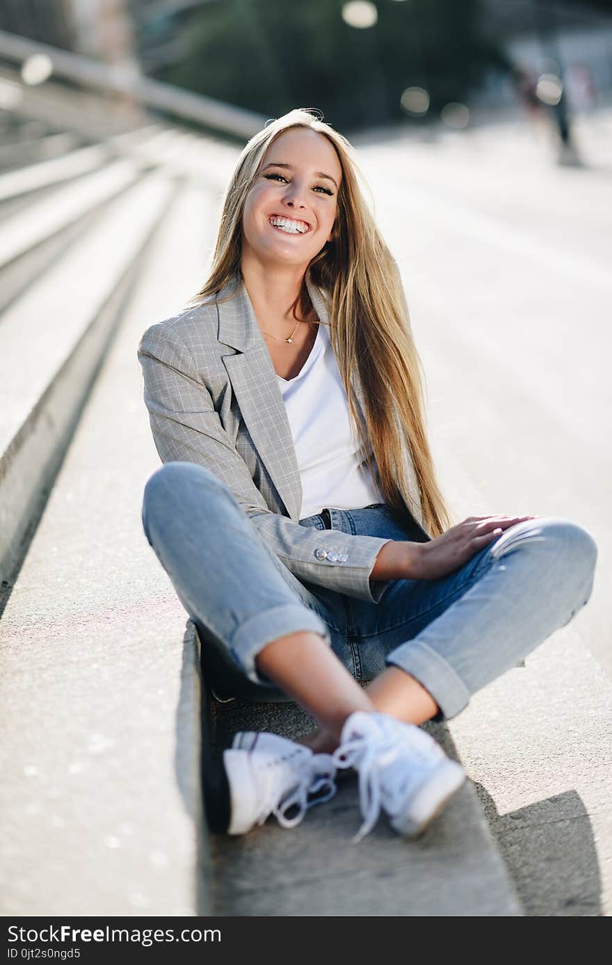 Beautiful young blonde woman smiling on urban steps.