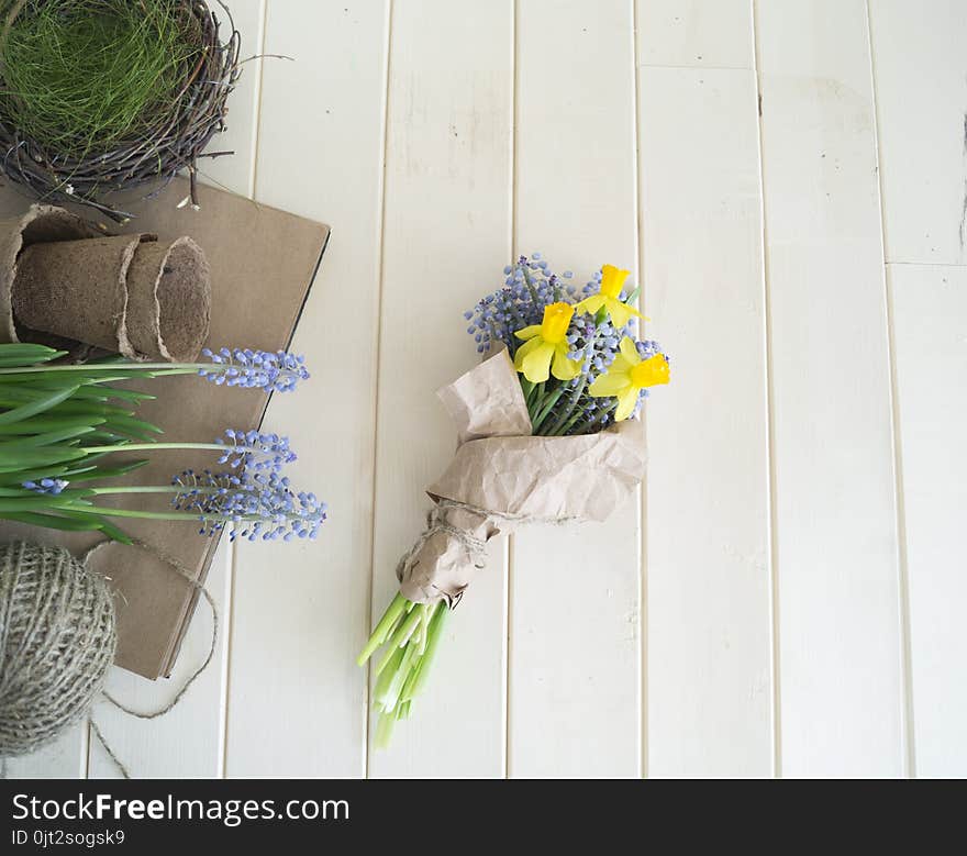 Children`s hands collect a bouquet as a gift. A gift for mom. Spring festive bouquet in a crafting package. Pruning flowers. The child is a florist. Wooden background. Field bouquet. Eco-style.