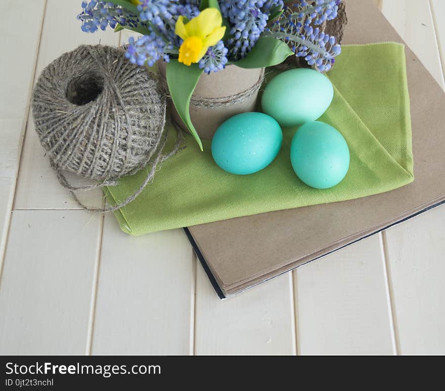 Bouquet of daffodils, tulips and Muscari.Easter. Easter eggs are blue and turquoise.The bird`s nest. Wooden background. The style of eco.Green,brown,blue, lilac and yellow.