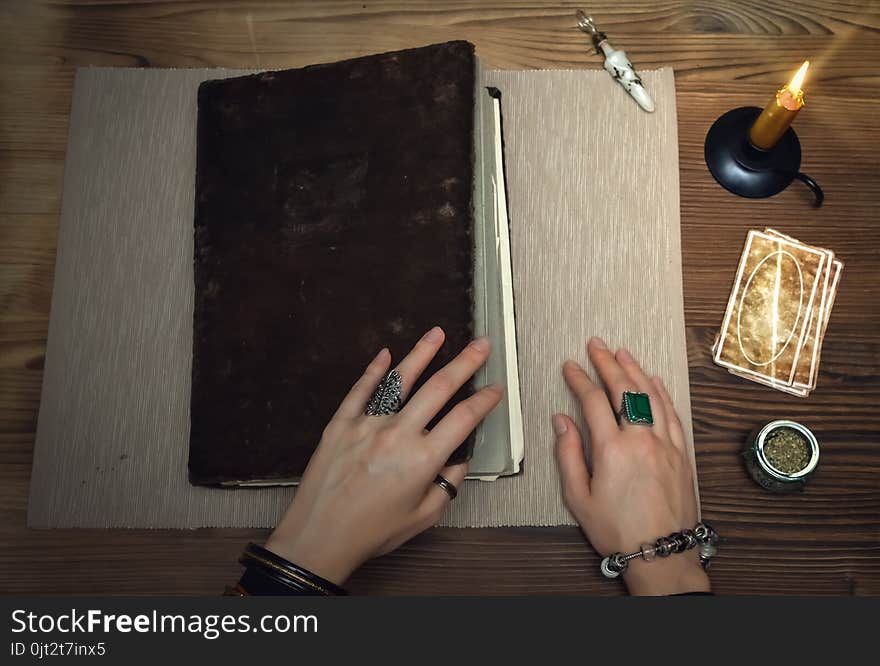 Book of magic with mystical light. Tarot cards on fortune teller desk table. Future reading. Woman witch open ancient magic scroll book and learn art of prediction on wooden table. Book of magic with mystical light. Tarot cards on fortune teller desk table. Future reading. Woman witch open ancient magic scroll book and learn art of prediction on wooden table.