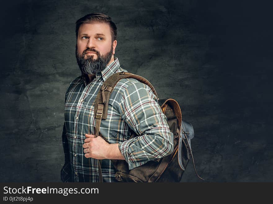 Portrait of bearded male dressed in a fleece shirt holds backpack on his shoulder. Portrait of bearded male dressed in a fleece shirt holds backpack on his shoulder.