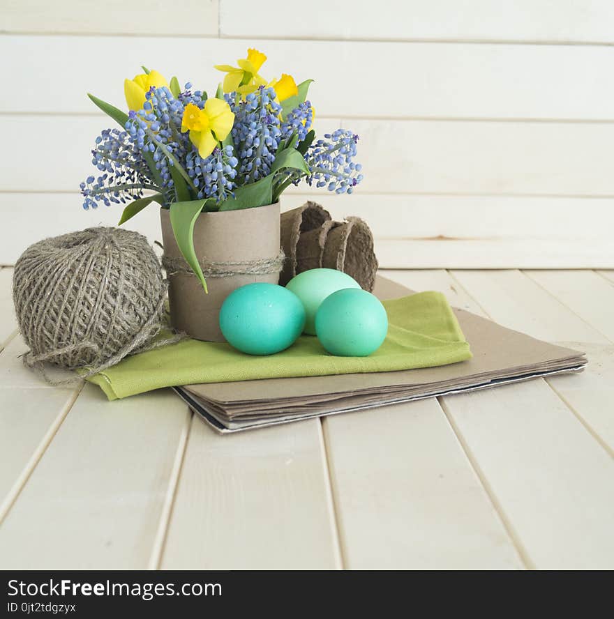 Bouquet of daffodils, tulips and Muscari.Easter. Easter eggs are blue and turquoise.The bird`s nest. Wooden background. The style of eco.Green,brown,blue, lilac and yellow.