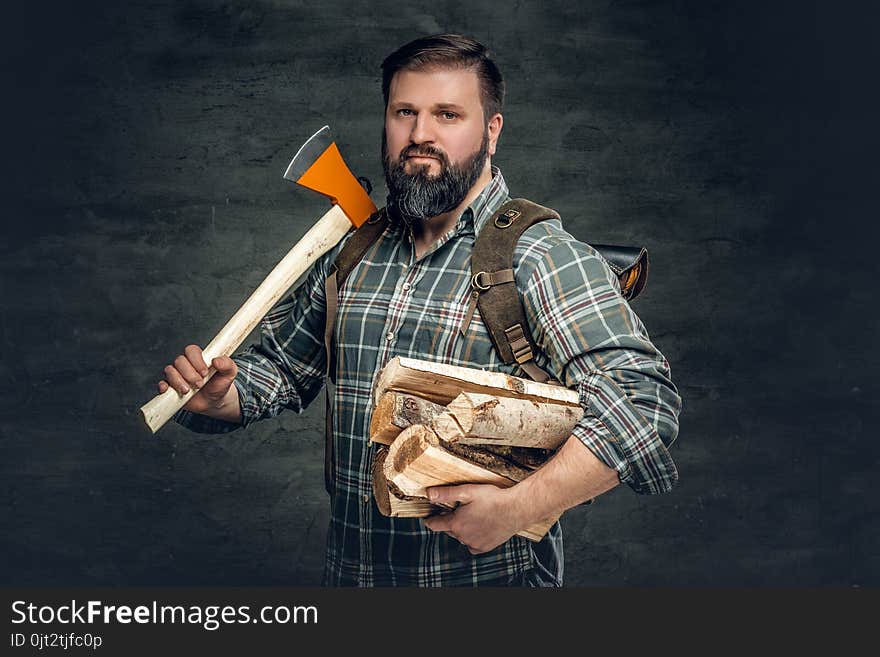 Portrait of brutal bearded hunter male holds an axe on his shoulder.