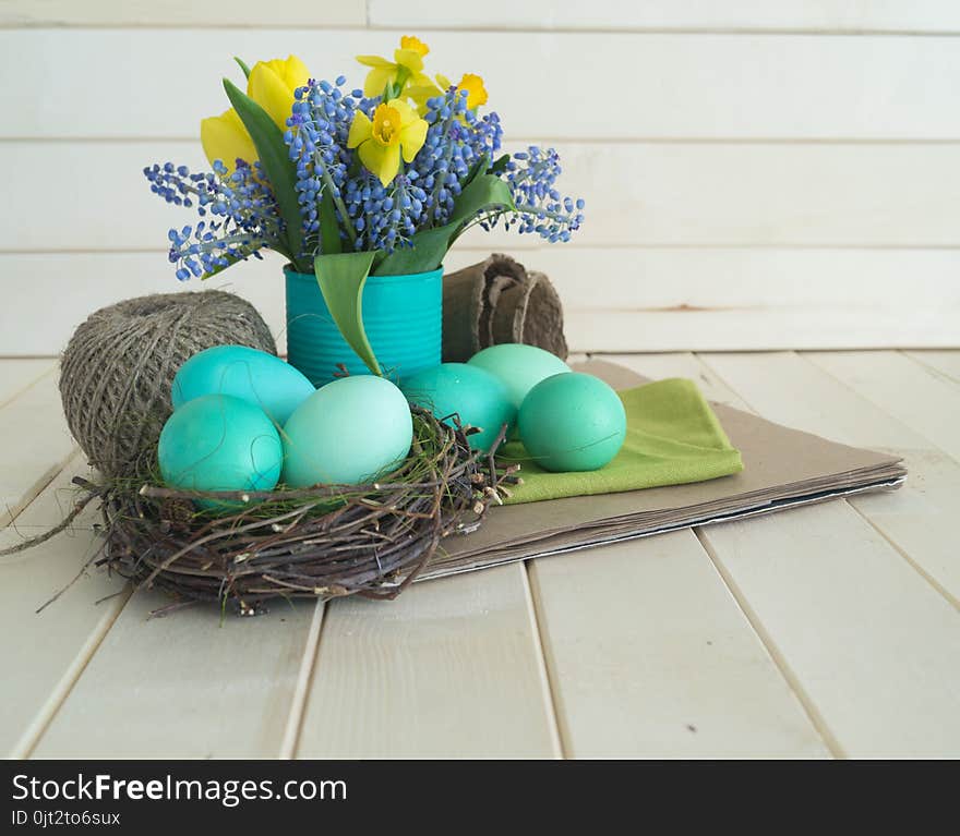 Bouquet of daffodils, tulips and Muscari.Easter. Easter eggs are blue and turquoise.The bird`s nest. Wooden background. The style of eco.Green,brown,blue, lilac and yellow.