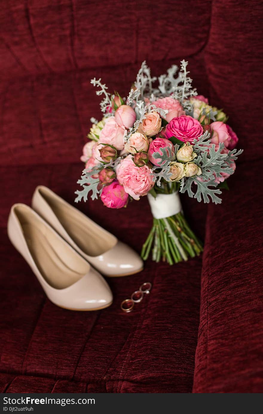 Wedding bouquet with purple and pink roses. Wedding accessories are lying on a red armchair. Wedding