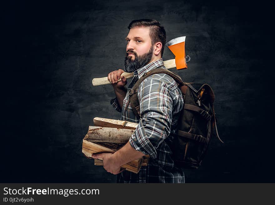 Portrait of brutal bearded hunter male holds an axe on his shoulder.