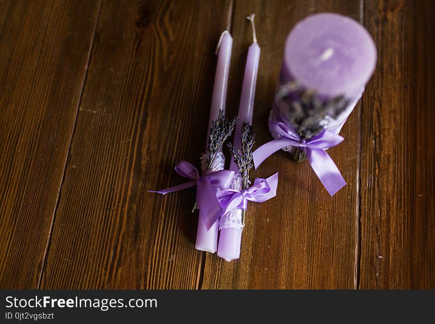 Three Purple Candles Decorated With Lavender Branches.