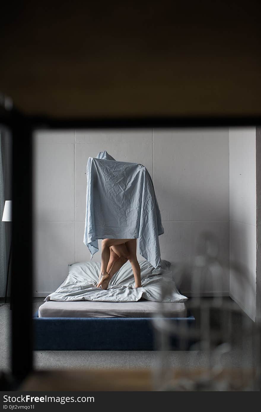 A couple in love is covered with a blue sheet on the bed.