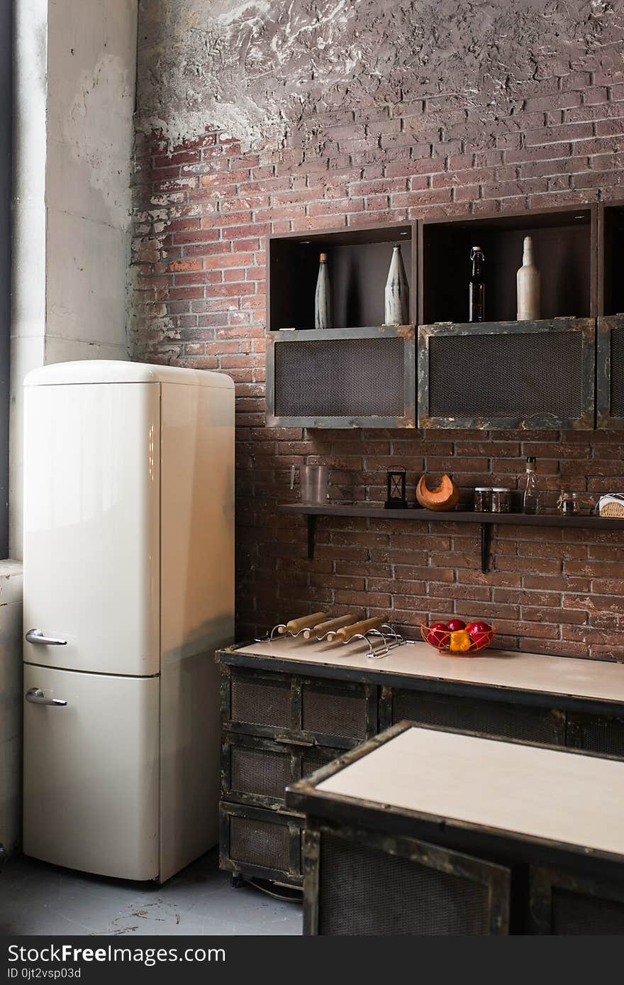 Part of the kitchen in loft style. White refrigerator on brick wall background. Loft