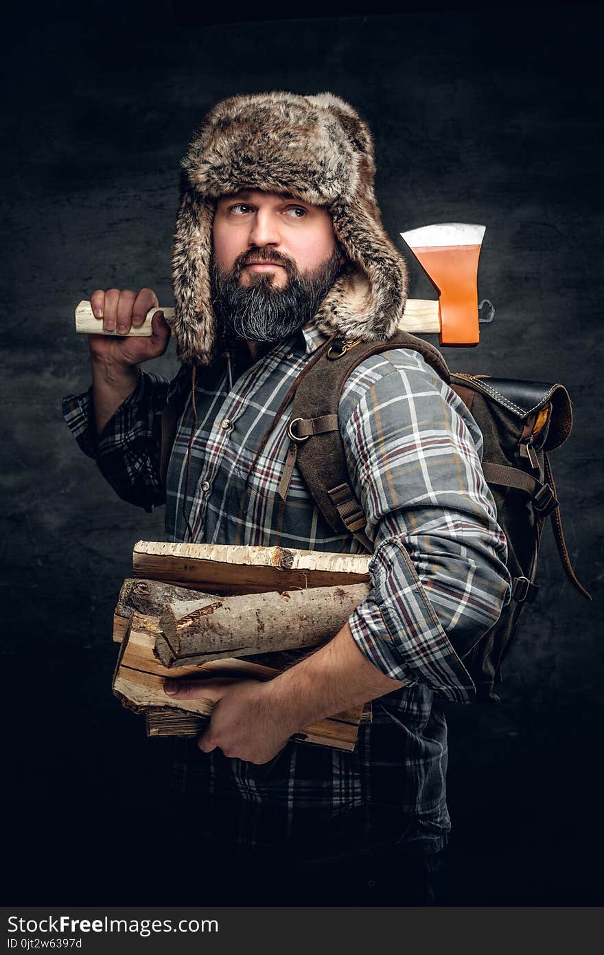 Portrait of brutal bearded hunter male holds an axe on his shoul