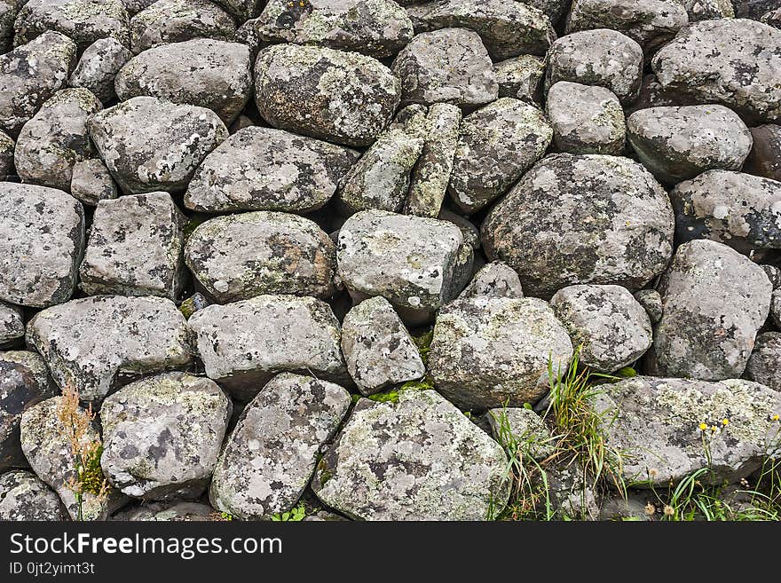 The stones lie in a pile covered with moss and lichen in close-up. The boulders and cobbles.