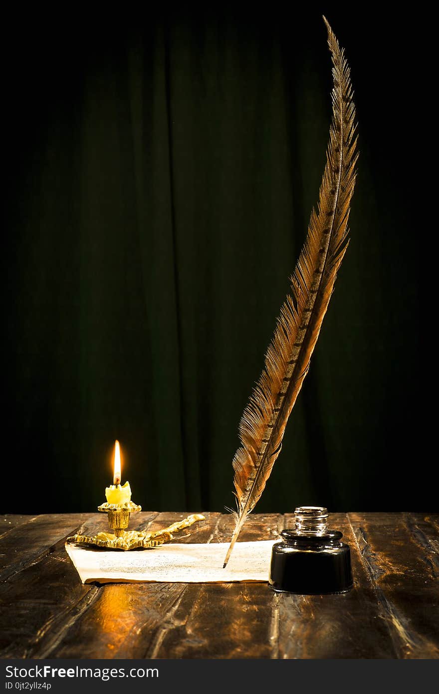 Education and writing concept, pen in ink bottle and candlestick with candle on wooden table on dark background. Education and writing concept, pen in ink bottle and candlestick with candle on wooden table on dark background.