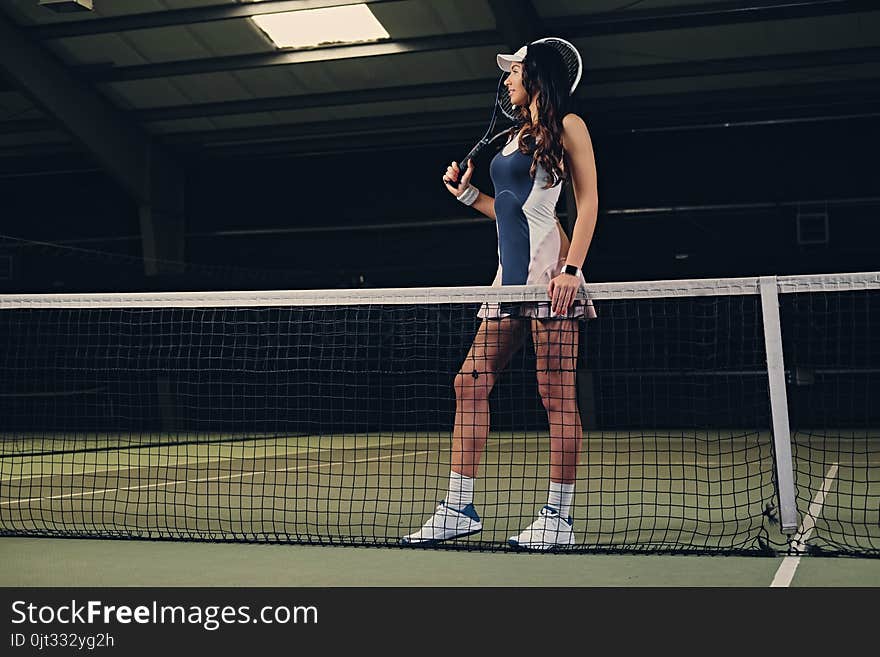 Female tennis player posing on an indoor tennis court.