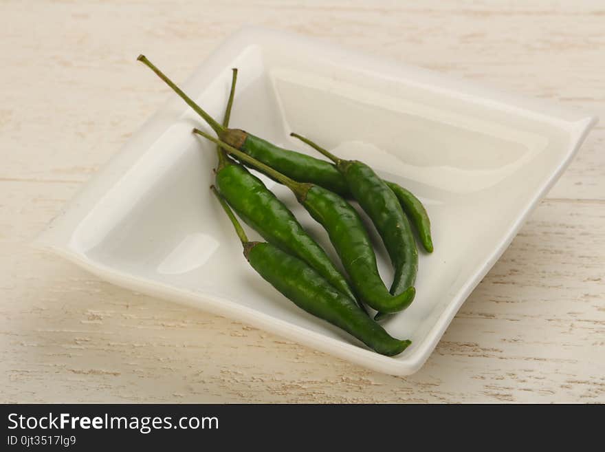 Green chili peppers heap in the bowl on wood background