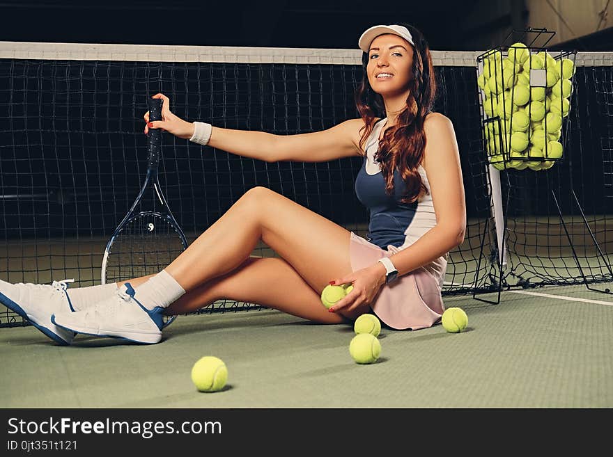 Female Tennis Player Sits In A Court And Holds Playing Rocket.