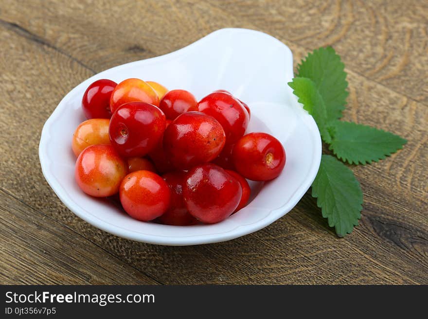 Sweet cherry in the bowl on wood background