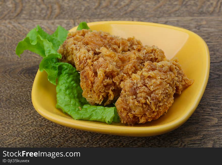 Crispy chicken wings with salad leaves on wood background