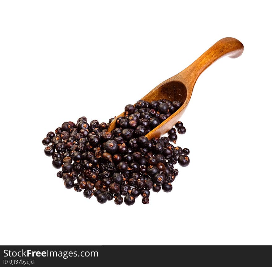 Dried Juniper berries on the wooden spoon.