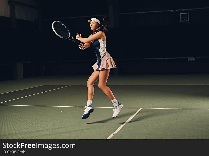 Female Tennis Player In Action In A Tennis Court Indoor.