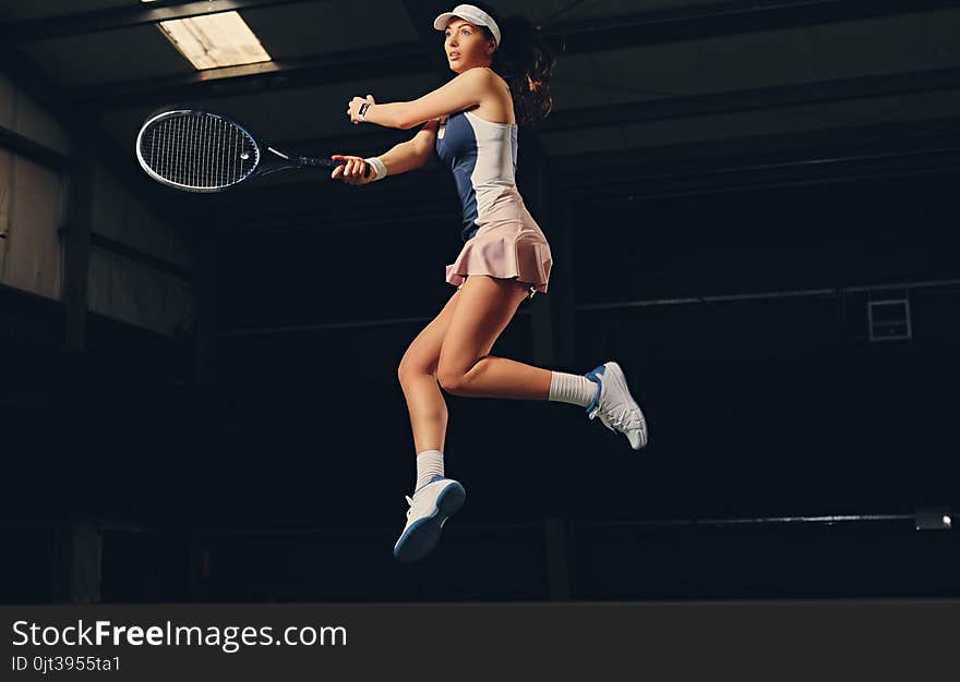 Female tennis player in a jump on a tennis court.