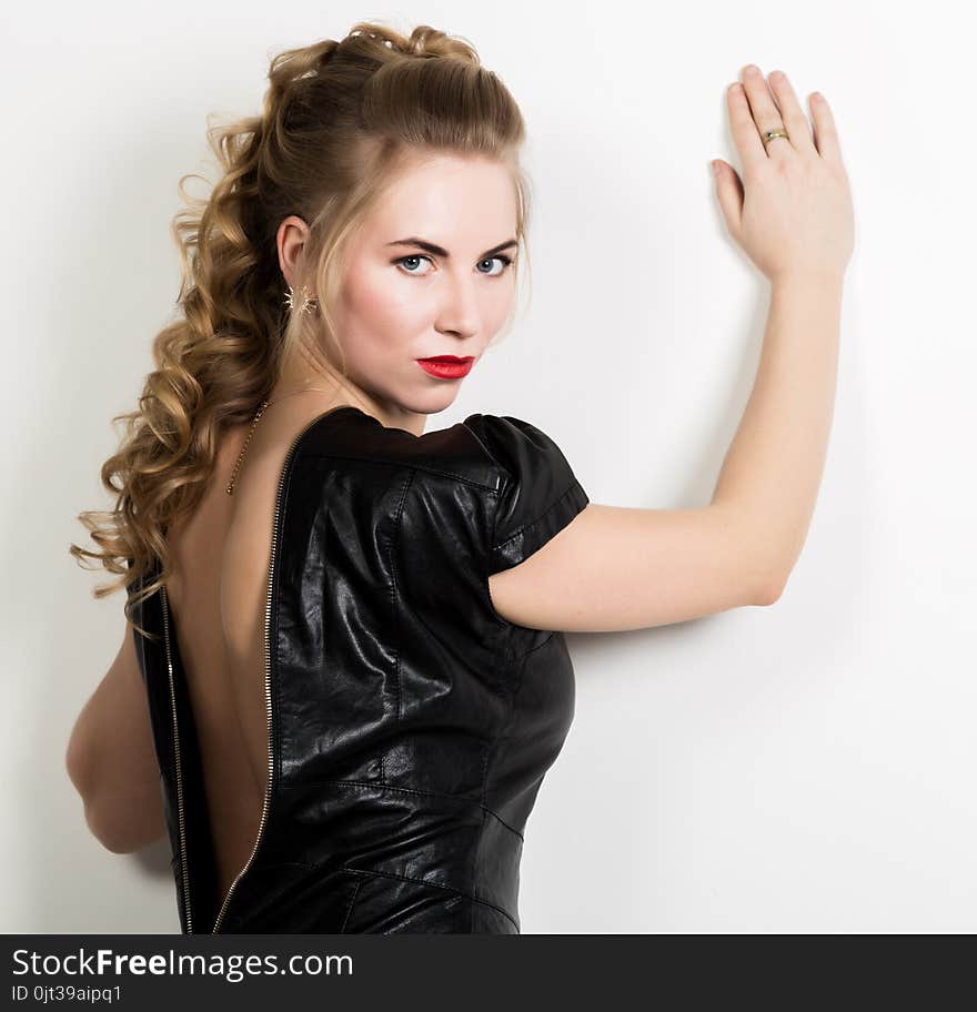 Beautiful Young Woman Wearing Short Leather Black Dress With Naked Back On A Light Background