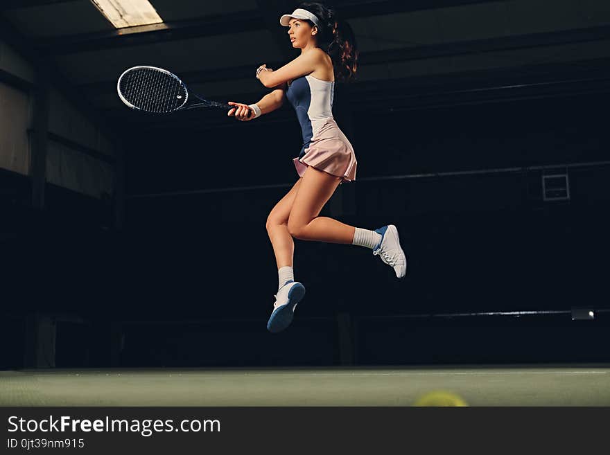 Female tennis player in a jump on a tennis court.