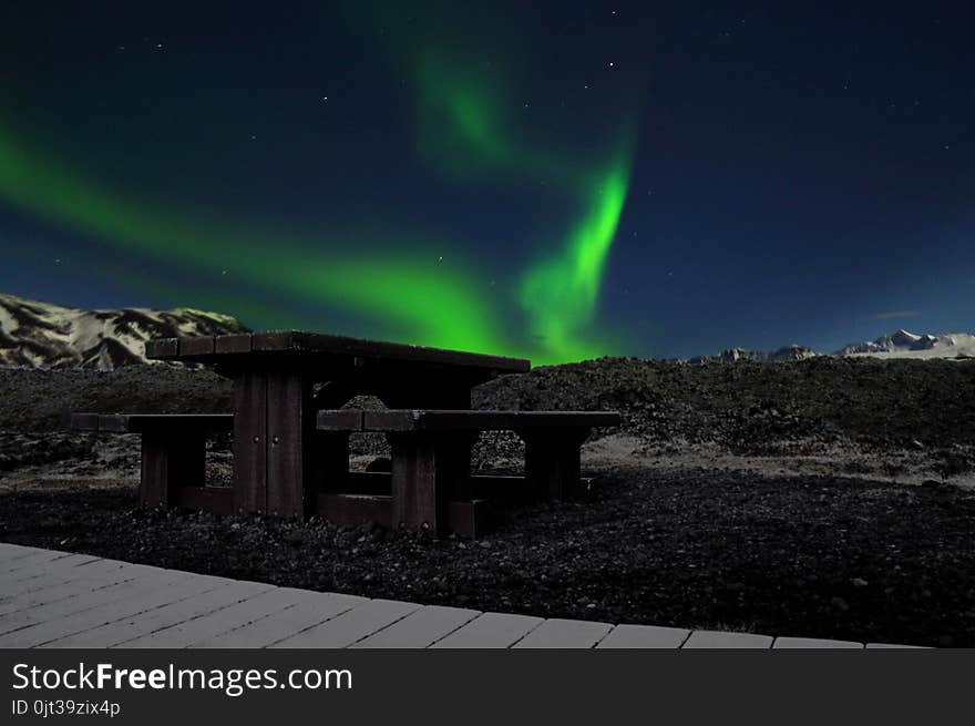 Picture of phenomenal green Aurora borealis in Iceland sky with a bench in the foreground