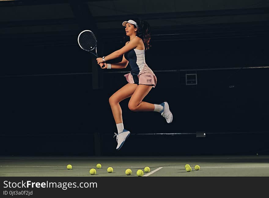 Female Tennis Player In A Jump On A Tennis Court.