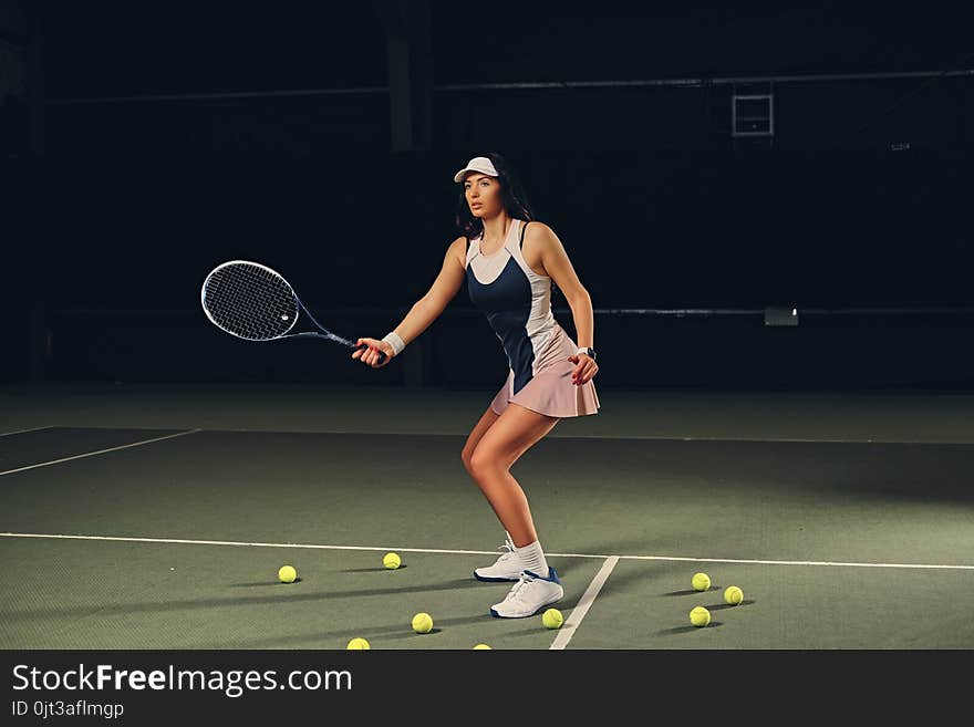 Female Tennis Player In Action In A Tennis Court Indoor.