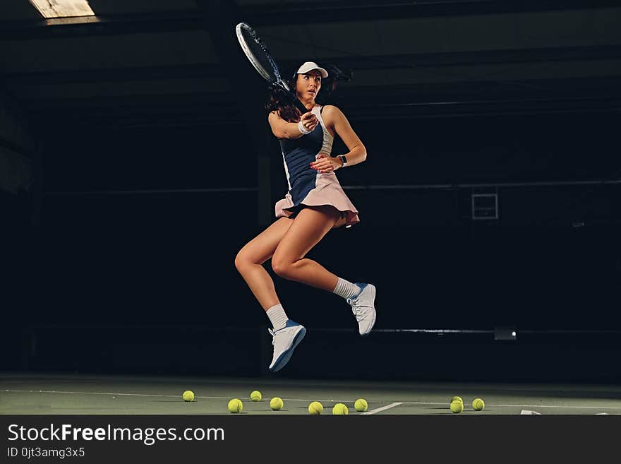 Female tennis player in a jump on a tennis court.