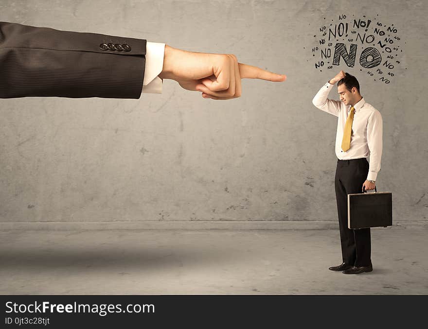 A young employee disagreeing and arguing with boss, feeling ashamed concept. A large hand pointing at businessman saying no. A young employee disagreeing and arguing with boss, feeling ashamed concept. A large hand pointing at businessman saying no