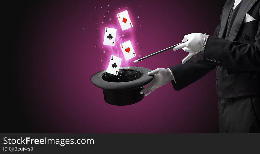 Magician making trick with wand and playing cards