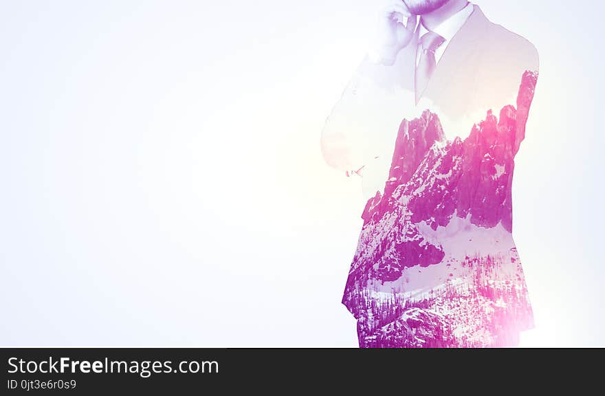 Young businessman in suit standing with sunny snowy mountain and trees graphic. Young businessman in suit standing with sunny snowy mountain and trees graphic.