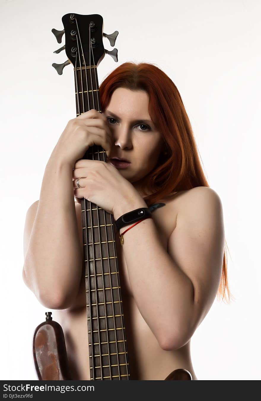 Nude rock woman holding electric guitar on a white background.