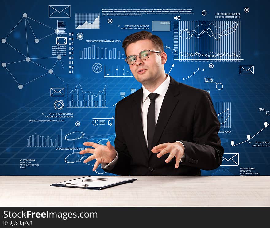 Young handsome businessman sitting at a desk with blue charts and data behind him