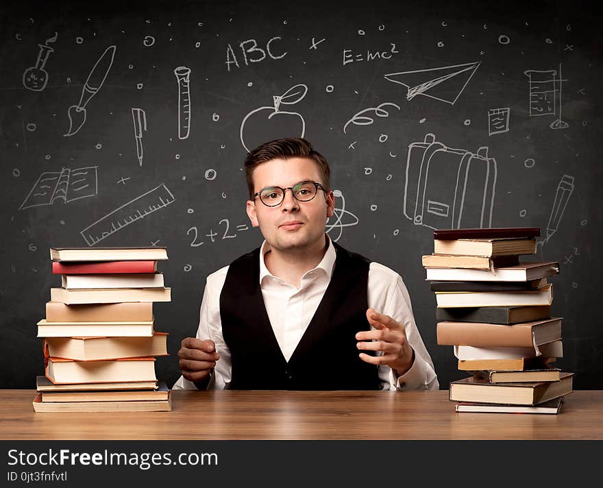 A passionate young teacher sitting at school desk with pile of books in front of blackboard drawn full of back to school items concept. A passionate young teacher sitting at school desk with pile of books in front of blackboard drawn full of back to school items concept.