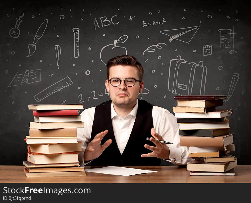 A passionate young teacher sitting at school desk with pile of books in front of blackboard drawn full of back to school items concept. A passionate young teacher sitting at school desk with pile of books in front of blackboard drawn full of back to school items concept.