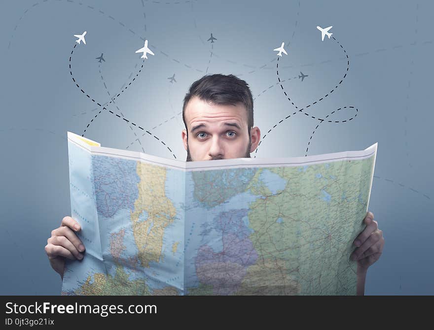 Handsome young man holding a map with little planes and their paths above him. Handsome young man holding a map with little planes and their paths above him