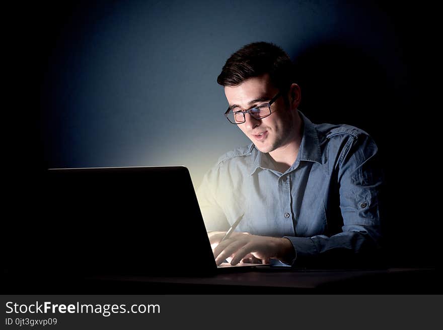 Young handsome businessman working late at night in the office with a dark background. Young handsome businessman working late at night in the office with a dark background