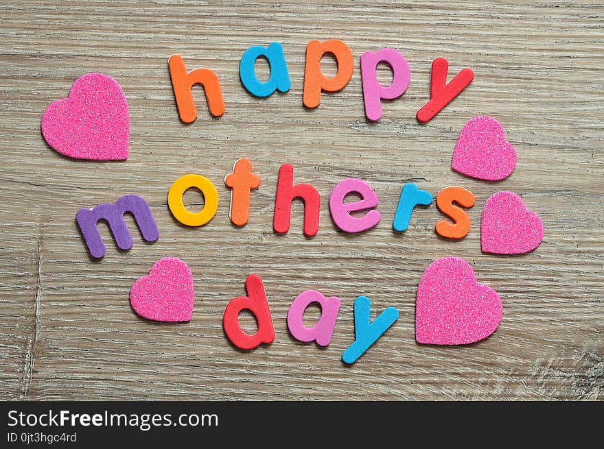 Happy mothers day in colorful letters on a wooden background with pink hearts. Happy mothers day in colorful letters on a wooden background with pink hearts